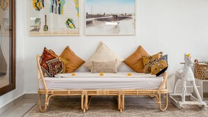 A rattan sofa with cushions, a wicker chair, and a white horse sculpture. - Canggu Garden House (Canggu)