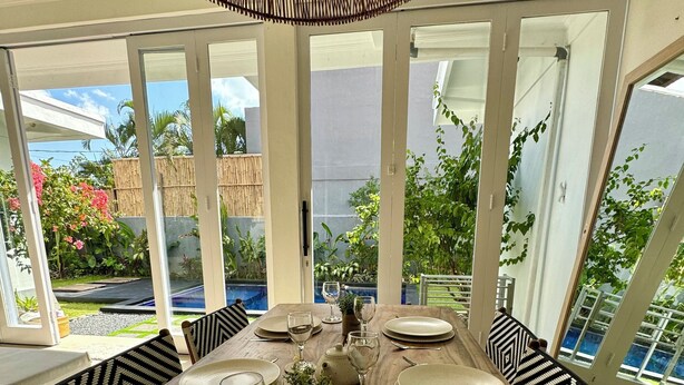 A dining area with a wooden table set for six, surrounded by chairs with patterned cushions. - Canggu Garden House (Canggu)