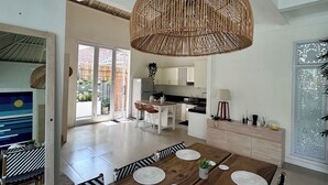 A spacious dining area with a wooden table, black and white striped chairs, and a large woven pendant light. - Canggu Garden House (Canggu)