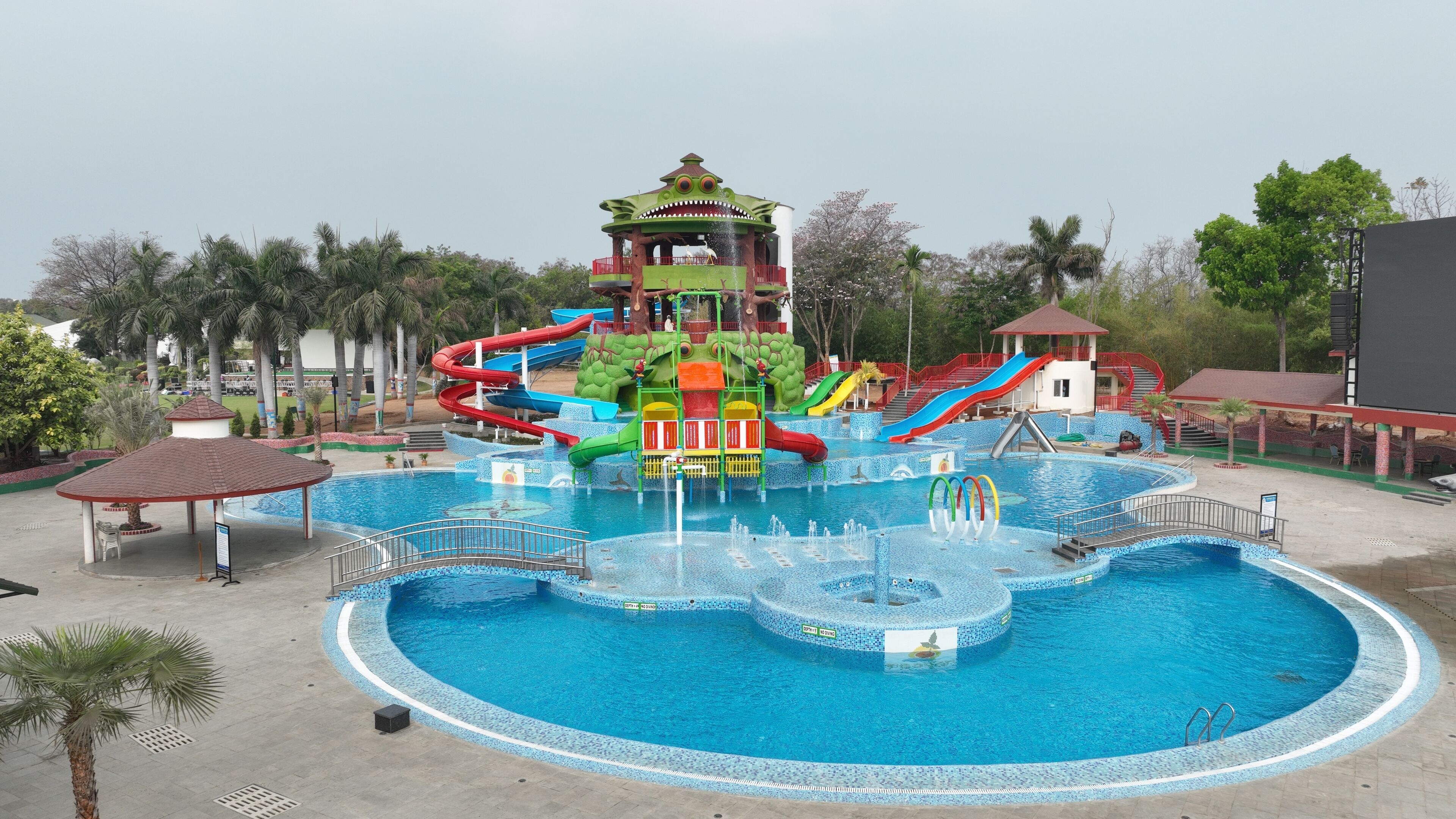 A water park with a central pool, multiple slides, and a frog-themed play structure.