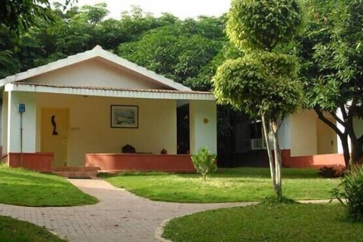A small, single-story building with a sloped roof, surrounded by a well-maintained lawn and a paved pathway leading to the entrance.