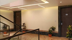 A modern hotel lobby with a marble floor, a glass railing, and potted plants. - Pragati Resorts (Shankarpalle)