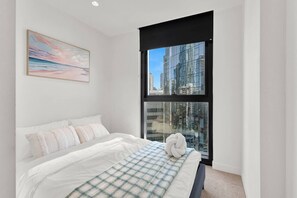 A modern bedroom with a large bed, a city view through a large window, and a painting on the wall. - Stylish Melbourne Central Escape - Balcony & Pool (Melbourne)
