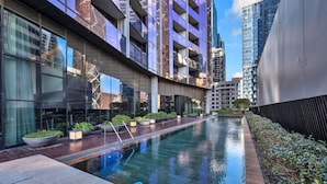 Un bâtiment moderne doté d’une piscine, de grandes fenêtres et d’un jardin bien entretenu.