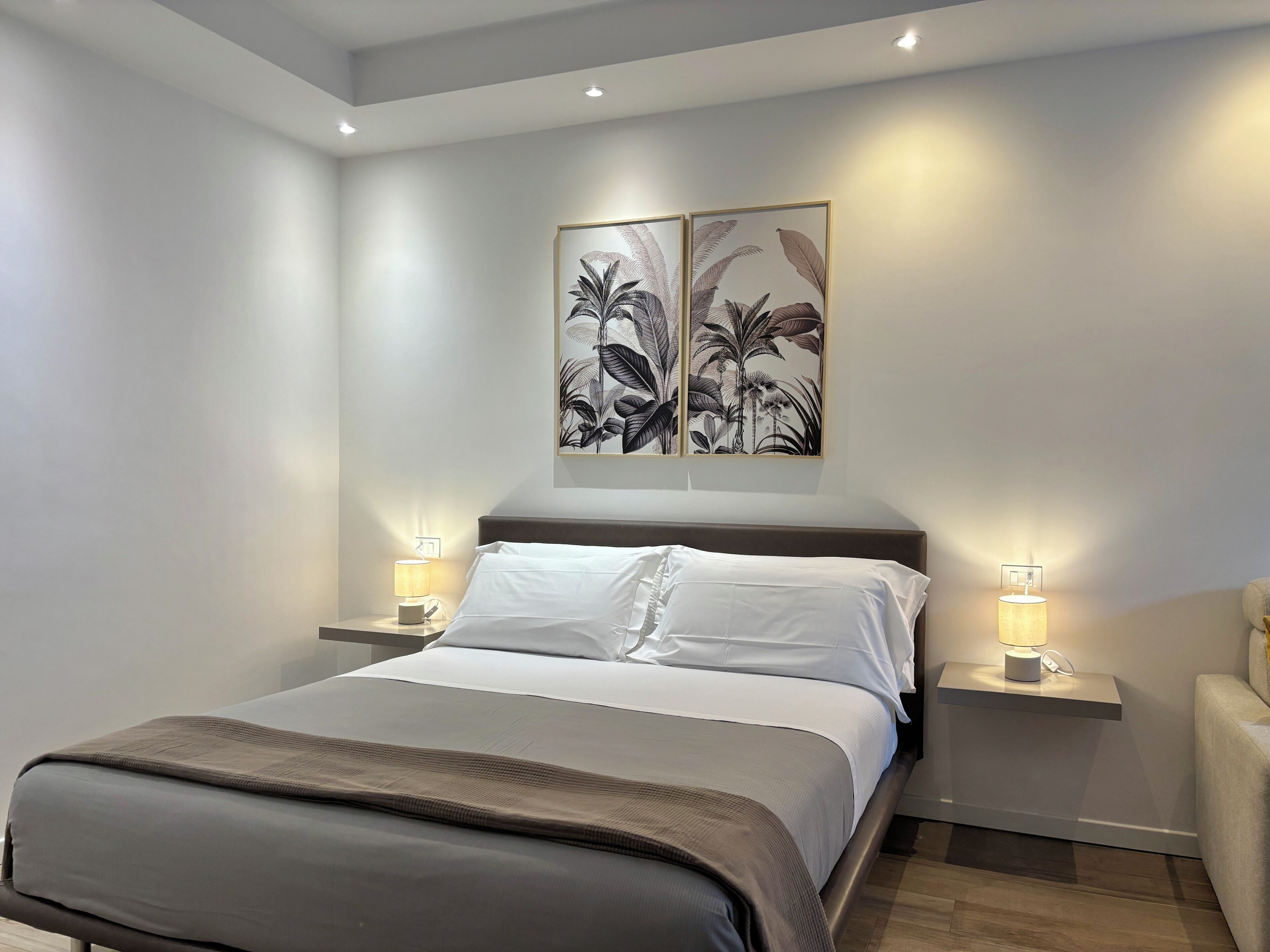 Un dormitorio moderno con una cama grande, dos mesitas de noche con lámparas y una obra de arte en la pared.
