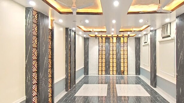A hallway with marble flooring, patterned columns, and recessed lighting. - Hotel Nandan Inn (Gaya)