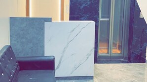 A modern lobby with a marble reception desk, a leather sofa, and a glass door leading to a staircase. - Hotel Nandan Inn (Gaya)