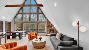 A spacious loft with high ceilings, large windows, a fireplace, and modern furnishings. - Bliss A-Frame, Heated Pool AxeThrow Sundeck Sauna HotTub FirePit (Jim Thorpe)