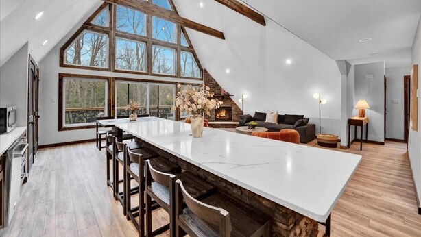 A spacious kitchen with a large island, wooden beams, and a fireplace. - Bliss A-Frame, Heated Pool AxeThrow Sundeck Sauna HotTub FirePit (Jim Thorpe)