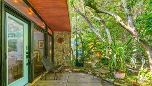 Un patio con pared de piedra, una banca y plantas en macetas.