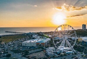 Une grande roue, un parking et une vue sur la côte au coucher du soleil.