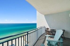 Ein Balkon mit Blick auf das Meer, ein Tisch mit Stühlen und ein kleiner Tisch mit einer Flasche und Gläsern.