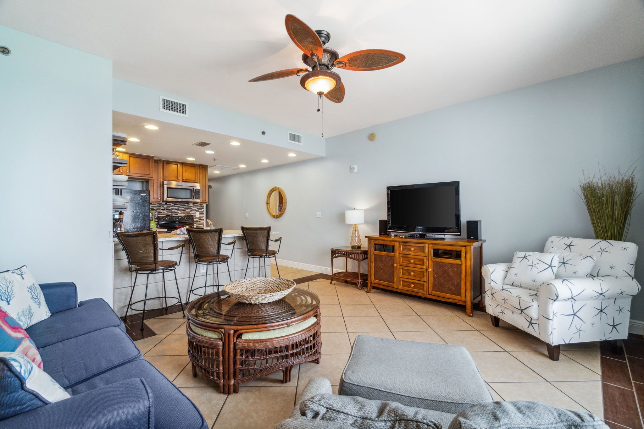 A living room with a sofa, armchair, TV, and a dining area with chairs and a table.