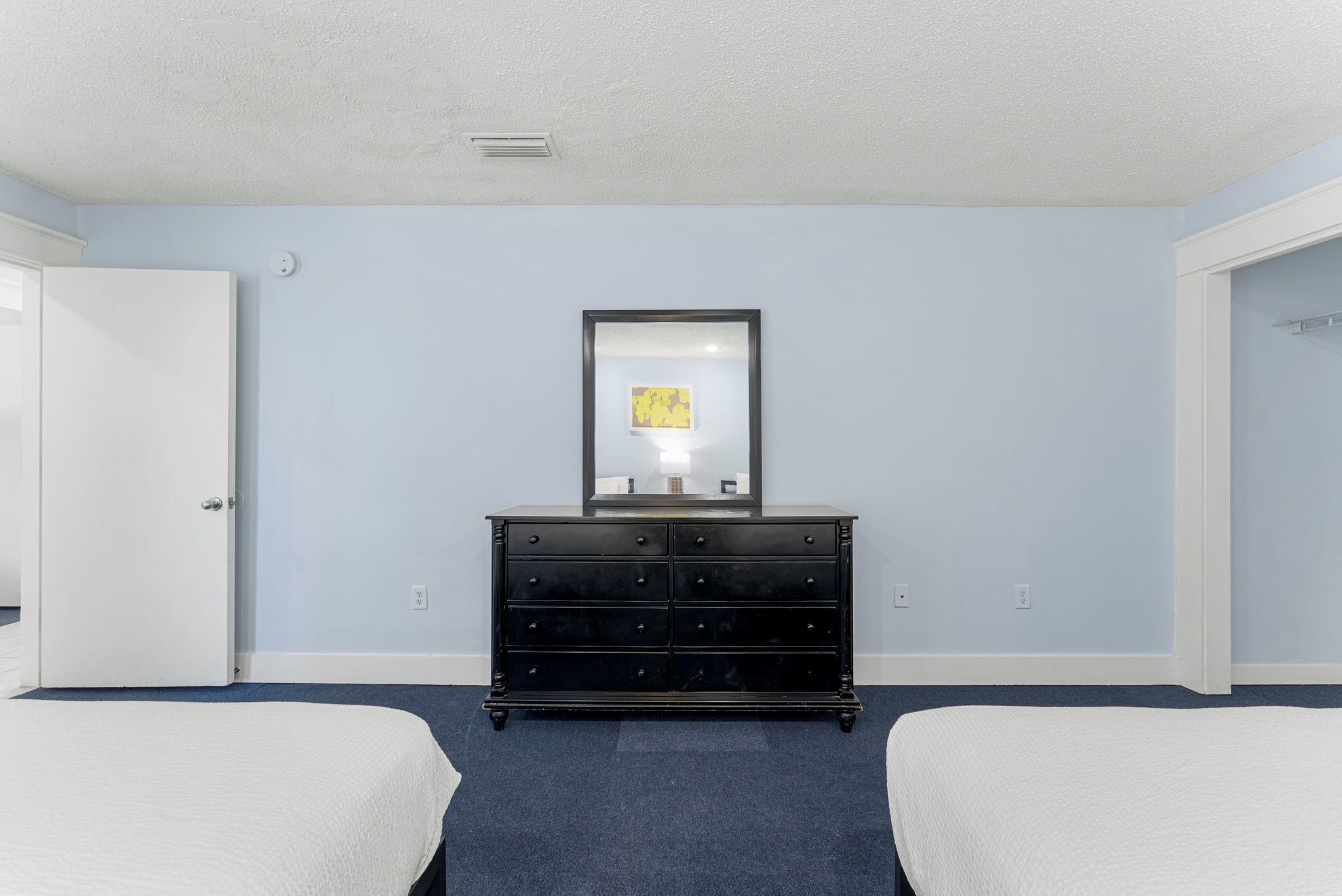 A hotel room with two beds, a dresser, and a framed picture on the wall.