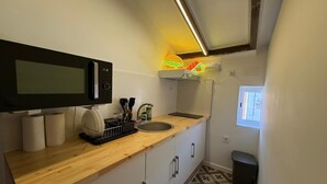 Cocina compacta con microondas, lavabo y encimera de madera.