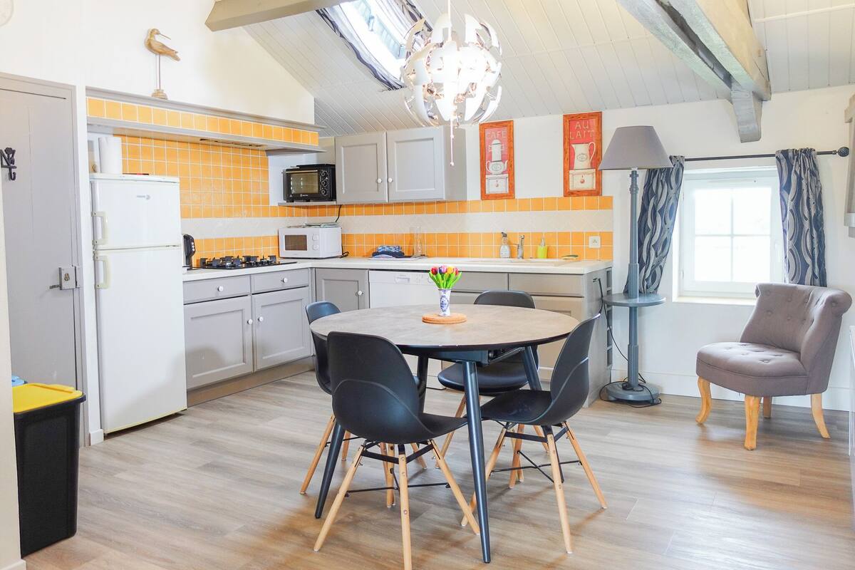 Una cocina compacta con microondas, tostadora y salpicadero de azulejos naranjas.
