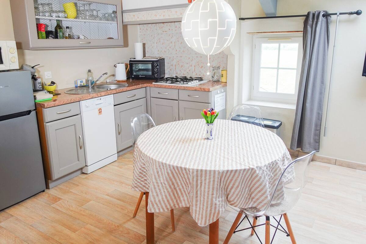 Cocina compacta con comedor, que incluye microondas, tetera y refrigerador pequeño.