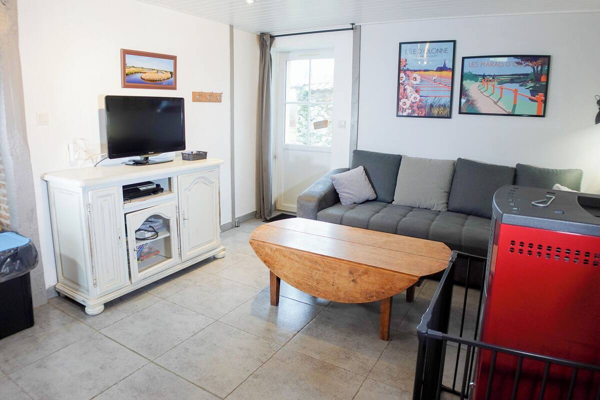 Una sala de estar con televisión, sofá, una mesa de centro y obras de arte en la pared.