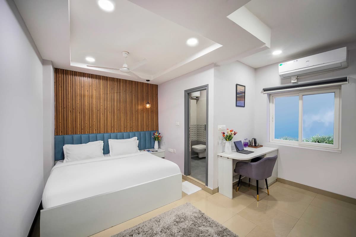 A modern bedroom with a bed, desk, and window.