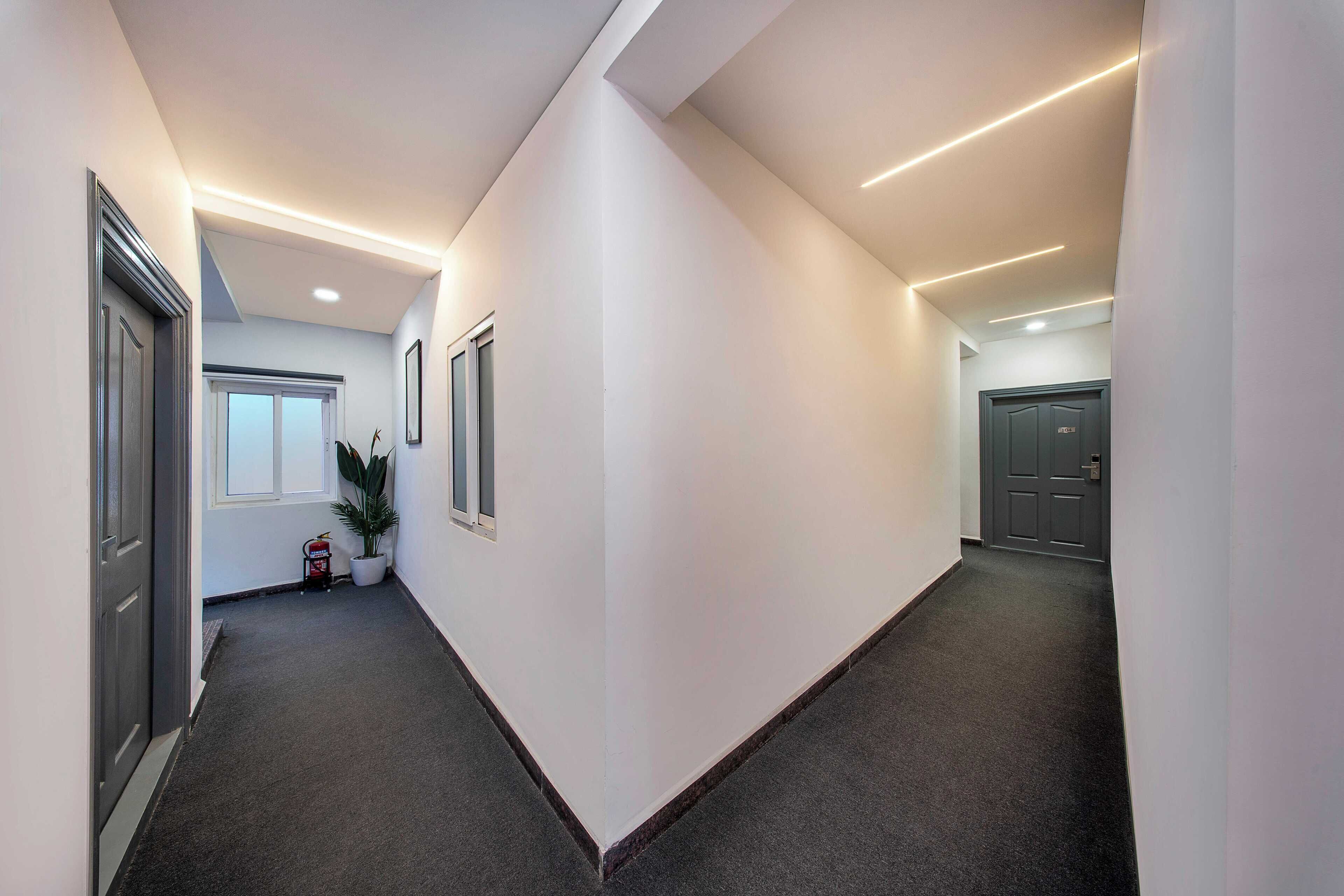 A modern hallway with dark carpeting, white walls, and recessed lighting.