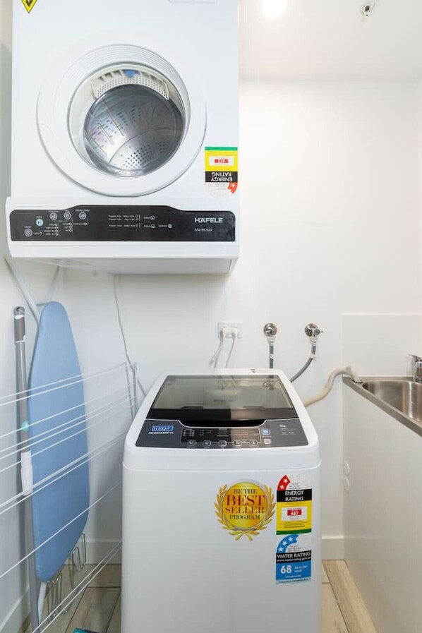 A compact laundry room with a front-loading washing machine and a top-loading dryer.