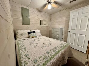 Une chambre à coucher avec un lit, une commode, un miroir et une porte.
