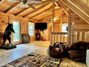 A rustic wooden cabin interior with a bear statue, a television, and a dog. - Dale Hollow Cabin · 3 Levels · Hot Tub · Huge Fire Ring · Sleeps 10 (Jamestown)
