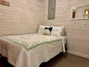 Une chambre à coucher avec un lit, un miroir et un mur en bois.