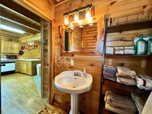 Ein Holzblockhaus-Innenraum mit Küchenzeile, Spüle und Ablagefläche mit Handtüchern und Pflegeprodukten.