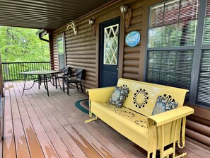 Eine Holzterrasse mit einer gelben Bank, einem Tisch und Stühlen.