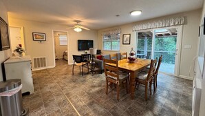 A spacious kitchen with a dining table and chairs, a refrigerator, and a trash can.