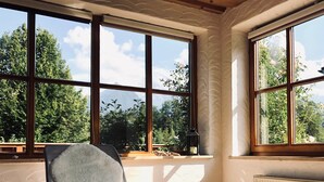 A room with large windows, a chair, a table, and a radiator. - Vacation apartment Watzmann, 80 m², 2 bedrooms, shower/WC,T (Bischofswiesen)