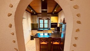 A kitchen with a stone-tiled floor, wooden ceiling, and a central island with bar stools. - Vacation apartment Watzmann, 80 m², 2 bedrooms, shower/WC,T (Bischofswiesen)