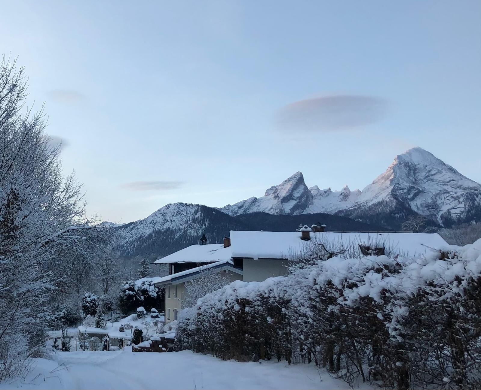 A snow-covered mountain landscape with a house in the foreground.