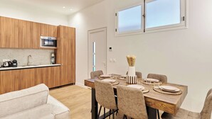 Una cocina moderna con armarios de madera, un microondas integrado y una zona de comedor con una mesa de madera dispuesta para cuatro.