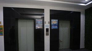 An elevator with digital displays and a QR code for smart rides. - Capital O Iconic Rooms @ Golden City (Bekasi)