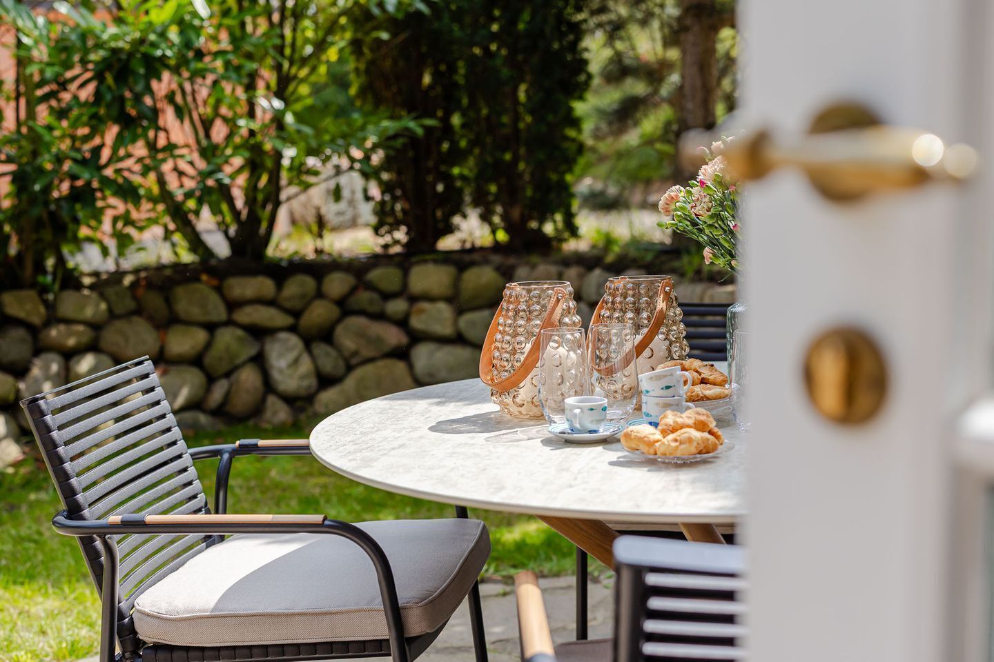 An outdoor dining area with a round table, chairs, and decorative glassware.