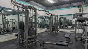 Une salle de sport équipée de divers appareils d’exercice, de bancs et de miroirs.