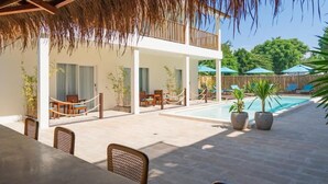 Un espace extérieur abrité comprenant une piscine, des chaises longues et une table à manger.