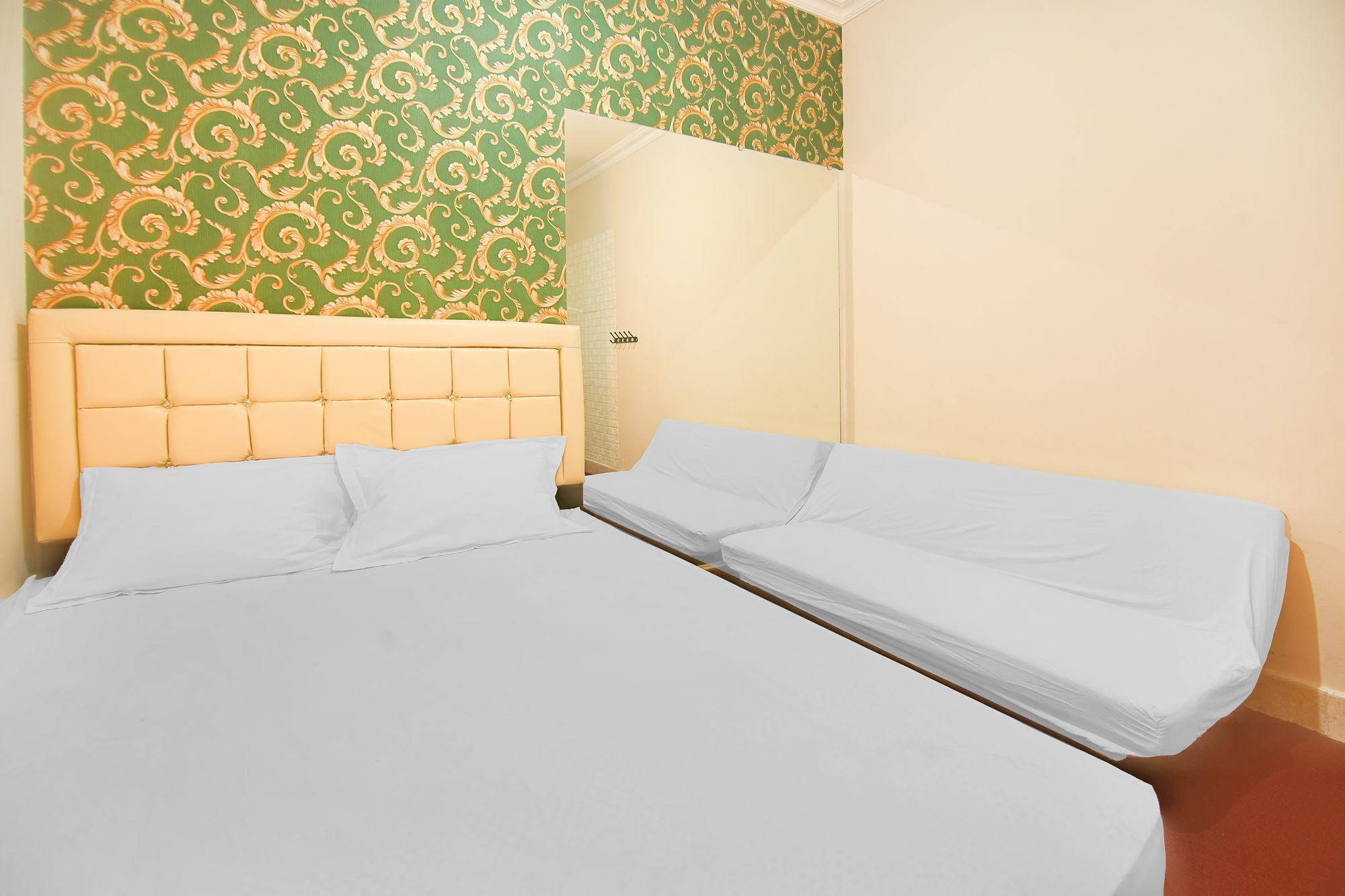 A hotel room with a large bed, a smaller bed, and a green patterned wall.