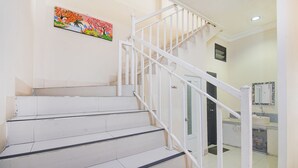 A staircase with white railings leading to a landing. A colorful painting is visible on the wall above the stairs. - OYO 94669 Hotel Puri Inn Panakkukang Makassar (Makassar)