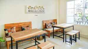 A modern cafe with wooden furniture, a large window, and a wall art piece. - OYO 94669 Hotel Puri Inn Panakkukang Makassar (Makassar)