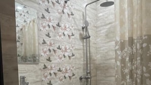 Un baño con inodoro, lavabo, ducha y azulejos con motivos florales.