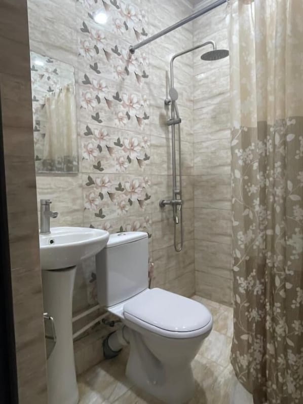 A bathroom with a toilet, sink, shower, and floral-patterned tiles. - Ruz & Arian Near Zvartnots Airport (Parakar)