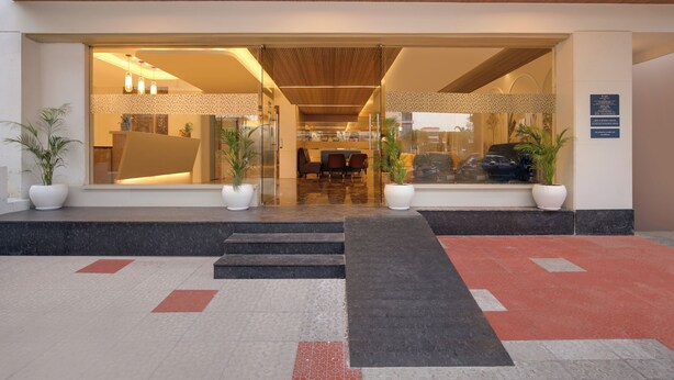 A hotel entrance with a modern design, featuring a wooden ceiling, glass doors, and a reception area with seating. - Keys Lite by Lemon Tree Hotels Krishna (Vijayawada)