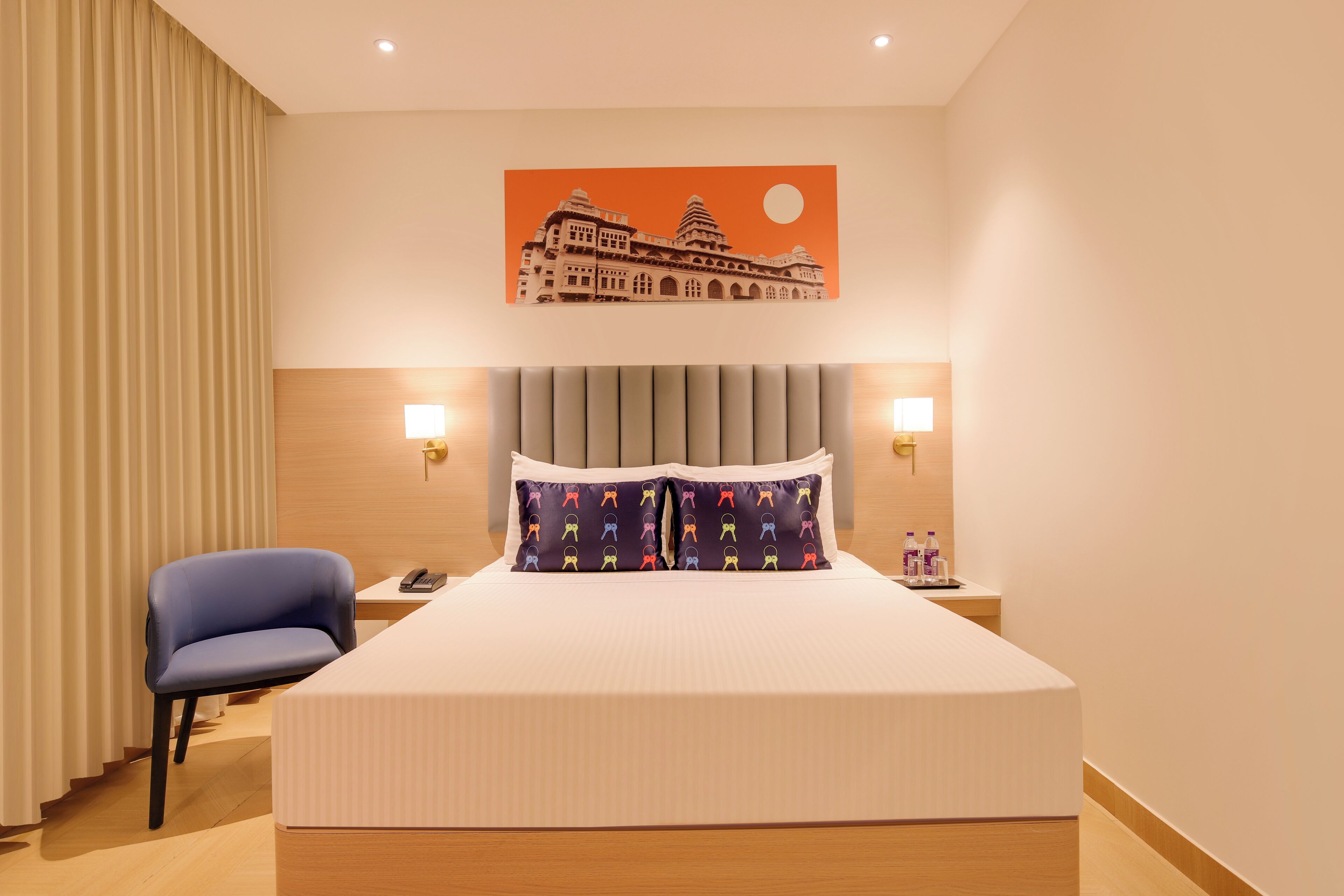 Ein Hotelzimmer mit einem großen Bett, einem Sessel, einem Nachttisch und einer Wandlampe.