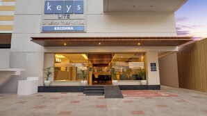 The exterior of the Keys Lite hotel by Lemon Tree Hotels, featuring a modern design with a prominent entrance, steps leading up to the door, and potted plants. - Keys Lite by Lemon Tree Hotels Krishna (Vijayawada)
