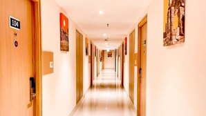 A hotel corridor with doors numbered 104 and 105, a clean, tiled floor, and artwork on the walls. - Keys Lite by Lemon Tree Hotels Krishna (Vijayawada)