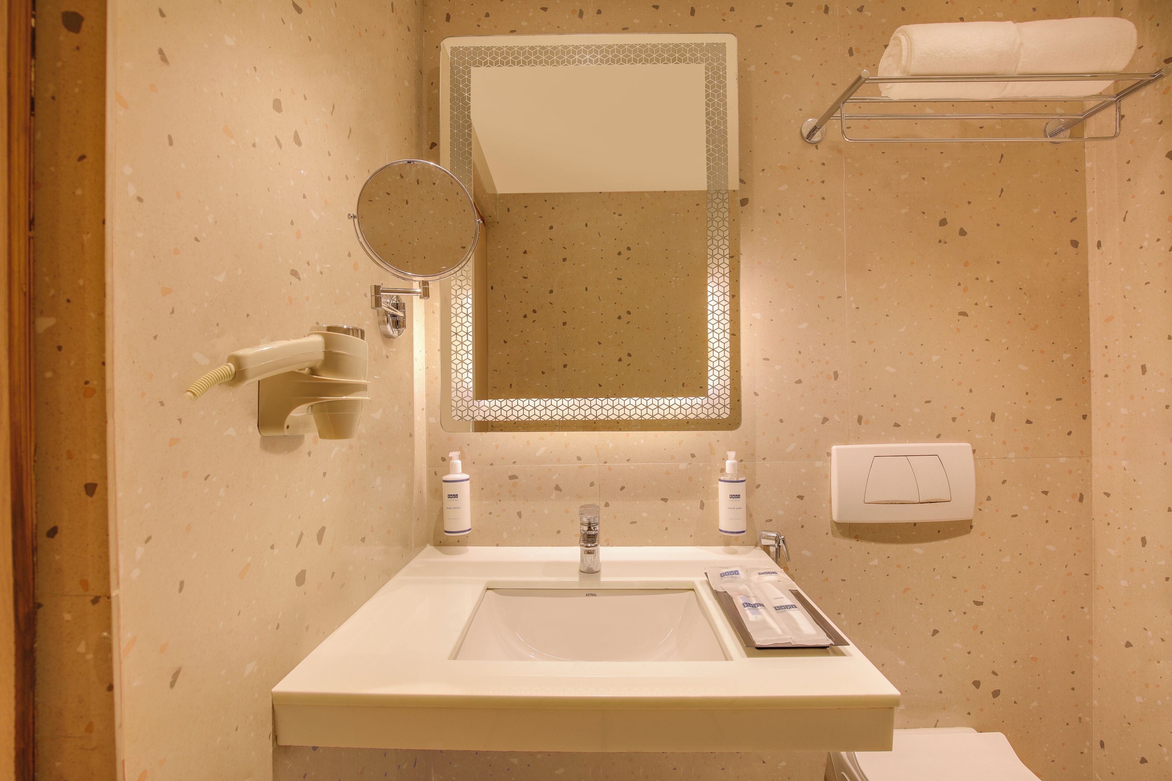 A bathroom with a sink, mirror, towel rack, and toiletries.