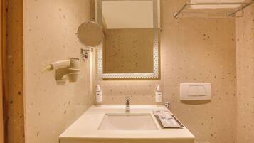 A bathroom with a sink, mirror, towel rack, and toiletries.